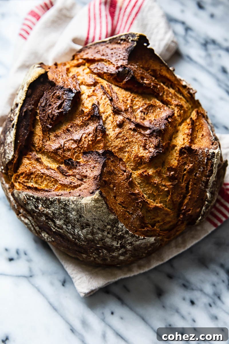 Rye Bread Mastery Baking with Rye Flour Unveiled 5 A freshly baked, dark rye bread loaf resting on a linen towel, ready to be sliced