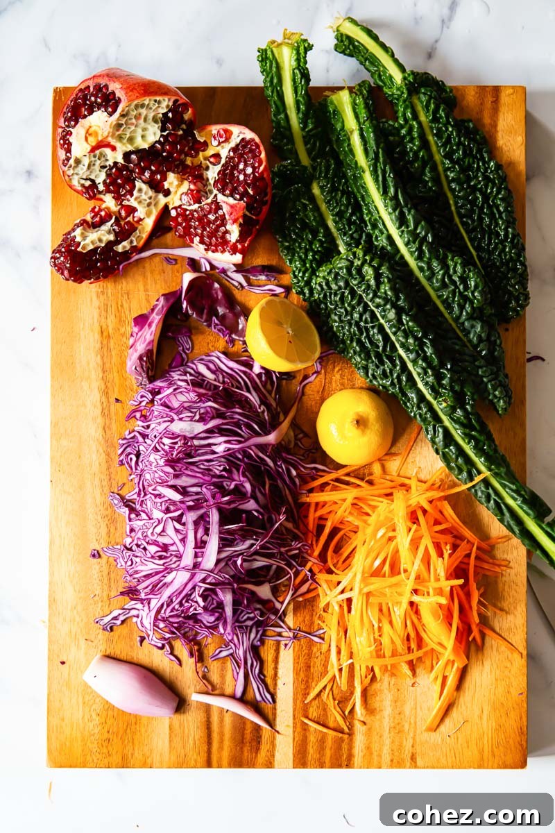 Sliced red cabbage, kale, carrots, pomegranate and shallots on cutting board 