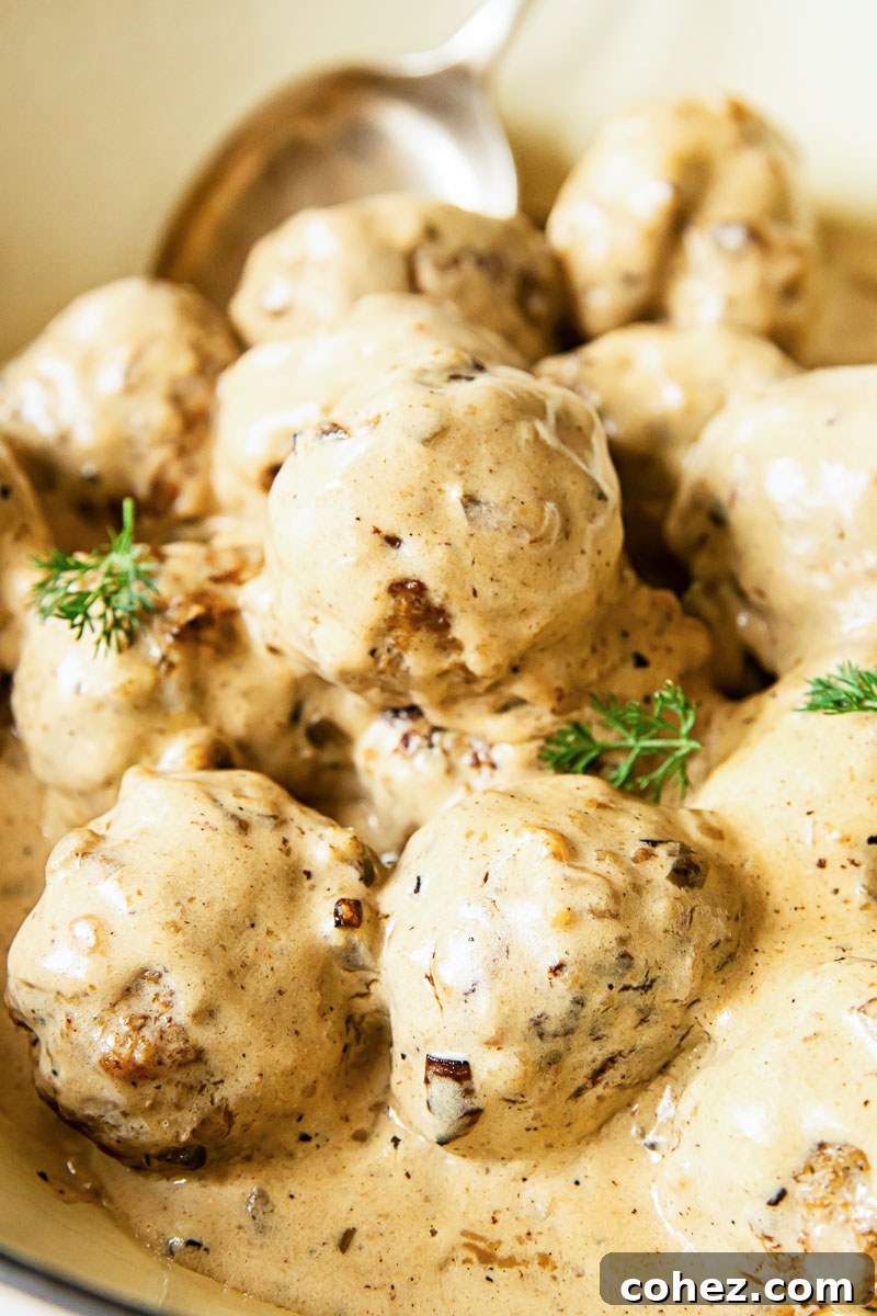 Close-up view of succulent Swedish Meatballs generously coated in their rich, creamy gravy.