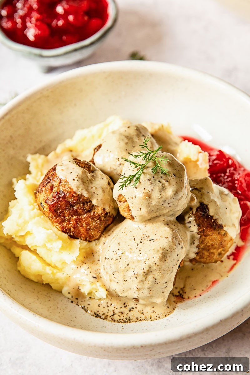 Platter of Swedish Meatballs served over fluffy mashed potatoes, drenched in their creamy sauce, ready to be enjoyed.