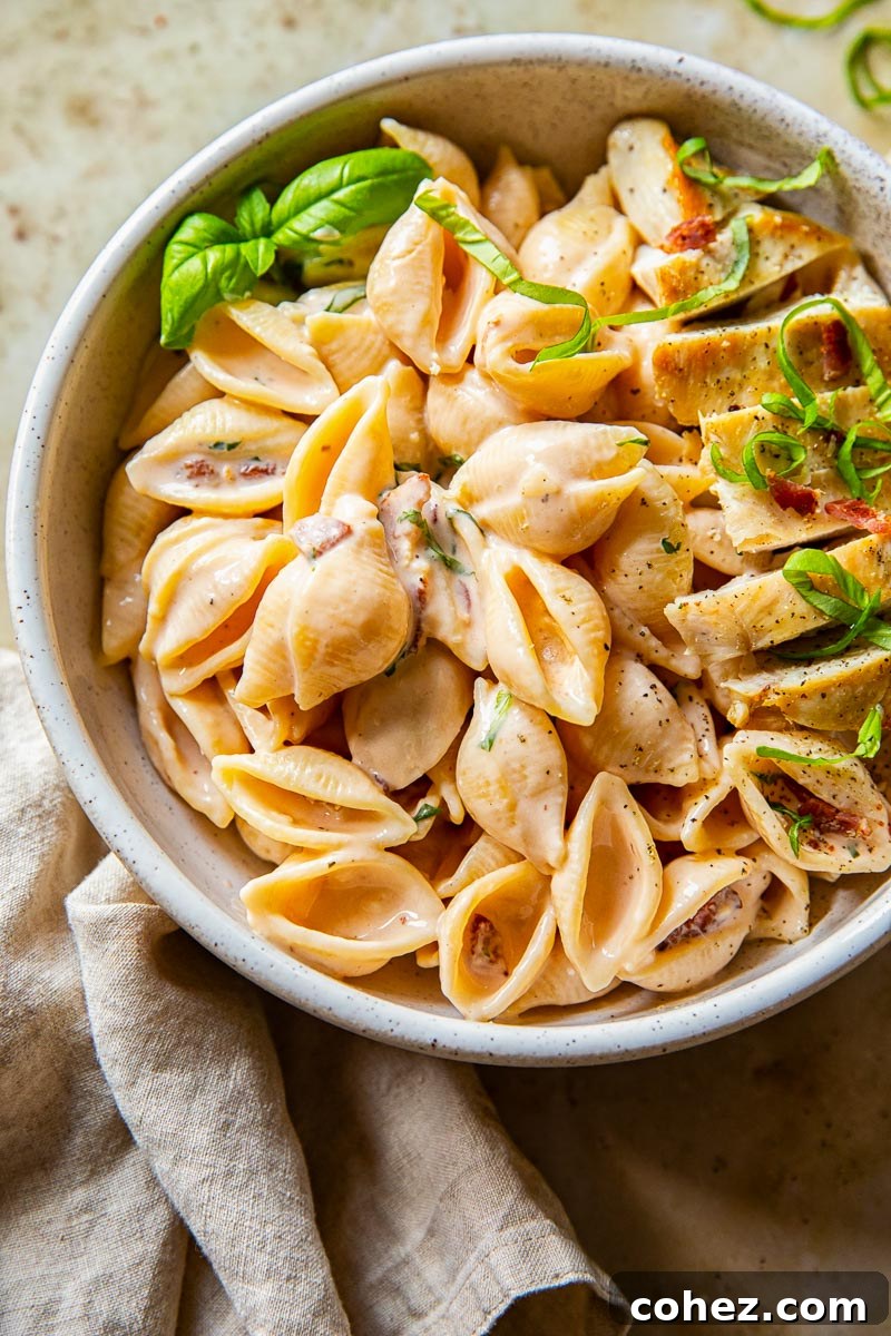 creamy bacon pasta topped with chicken breast and basil
