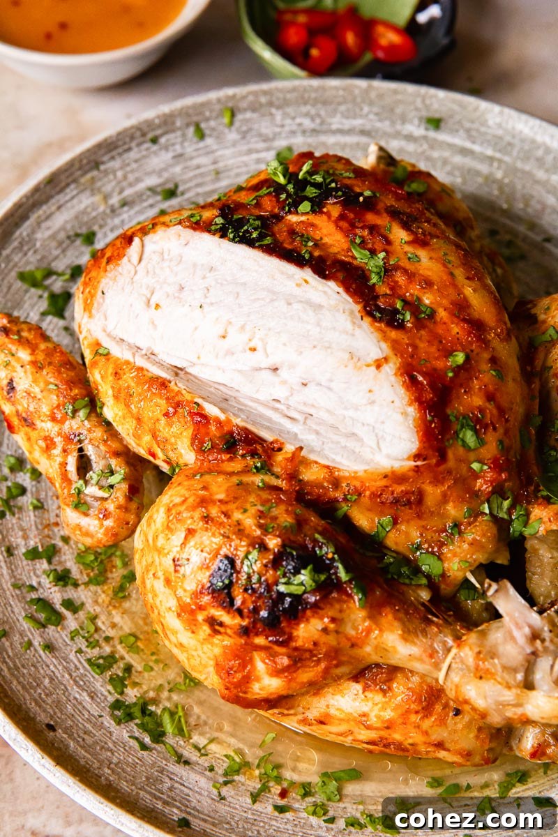 Whole chicken on a platter with a slice of breast meat visible, highlighting its juiciness and delicious glaze.