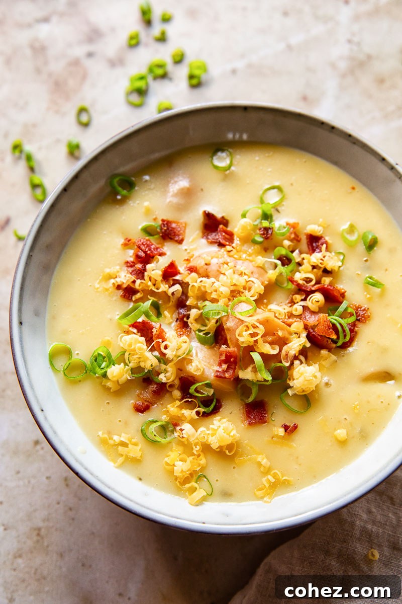 Creamy Instant Pot Potato Soup topped generously with crispy bacon bits, fresh green onions, and grated cheddar cheese, served in a rustic bowl.
