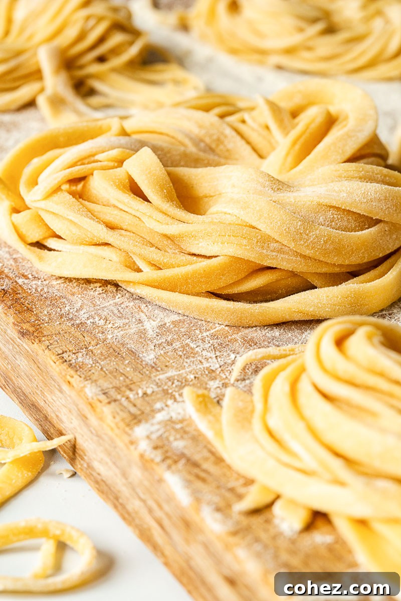 Bundles of freshly made tagliatelle pasta, neatly coiled and dusted with flour on a wooden surface.