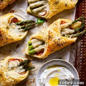 cheese and asparagus puff pastry pockets on baking sheet a small dish with dip