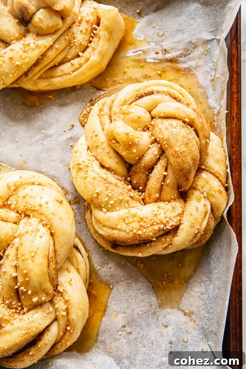 Unbaked cinnamon buns neatly arranged on a baking sheet, ready for the oven