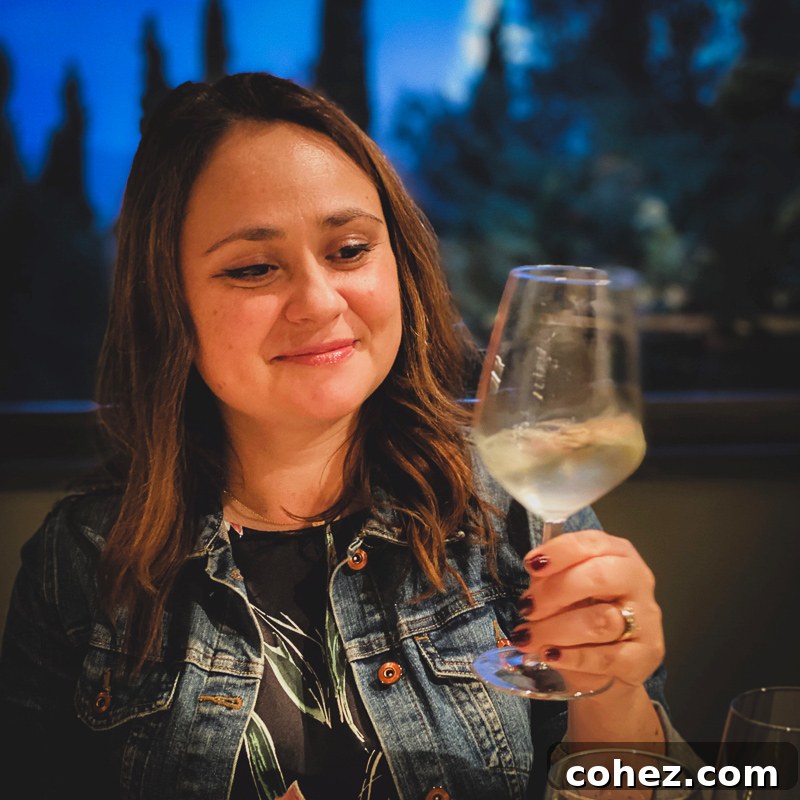 A woman holding a glass of crisp white wine, enjoying a tasting experience