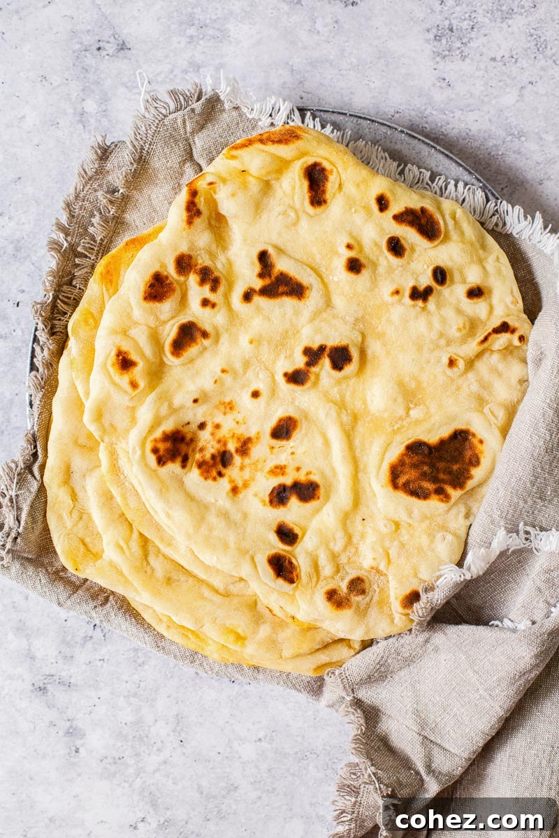 Warm pita breads stacked and wrapped in a grey cloth napkin, ready to be served.