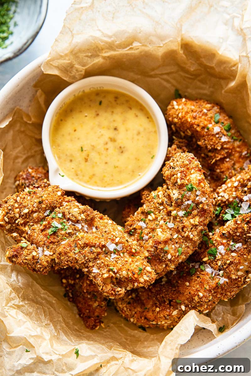 Golden Air Fryer Chicken Tenders and Tangy Honey Mustard 2 Crispy golden brown air fryer chicken tenders served with a side of creamy honey mustard dipping sauce.