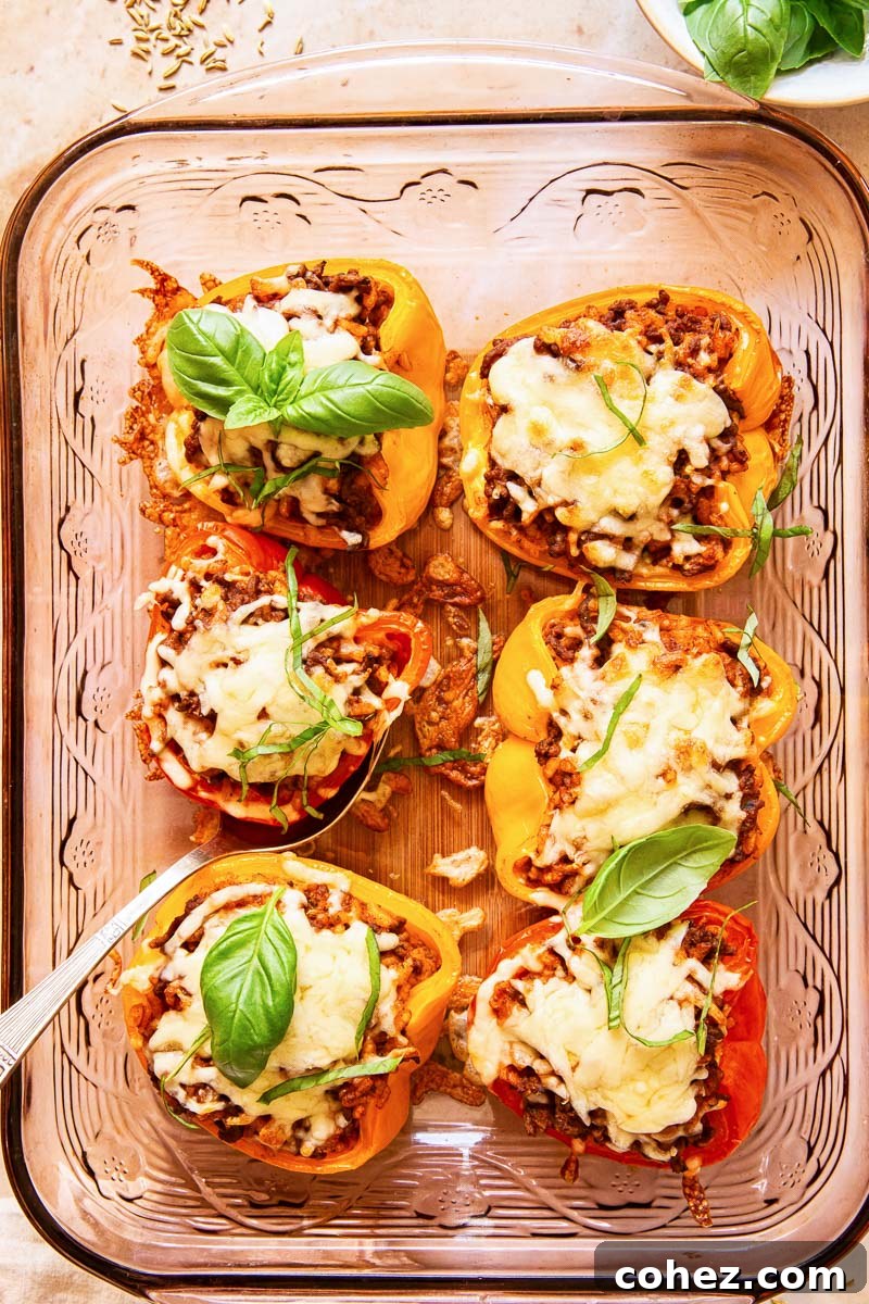 stuffed bell peppers topped with melted cheese and fresh basil in a pan