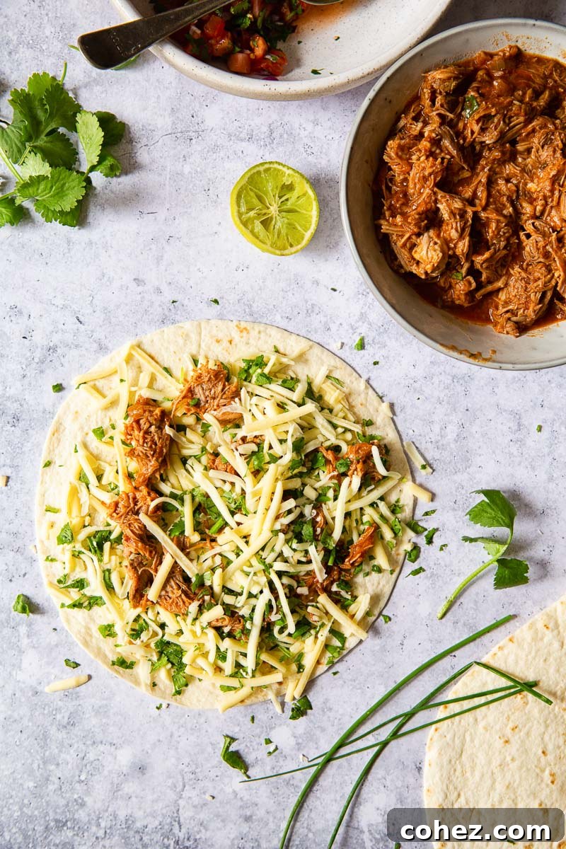 a tortilla topped with grated cheese and pulled pork and pulled pork in grey bowl