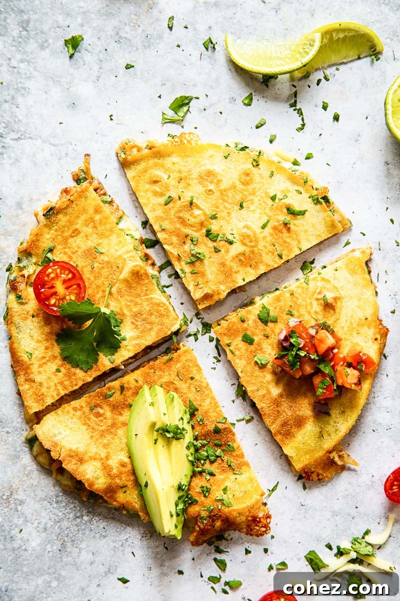 cheese quesadilla cut into quarters and topped with sliced avocado and pico de gallo on grey surface