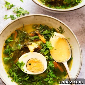 A vibrant green soup topped with fresh greens and a perfectly halved hard-boiled egg, served in a rustic bowl.