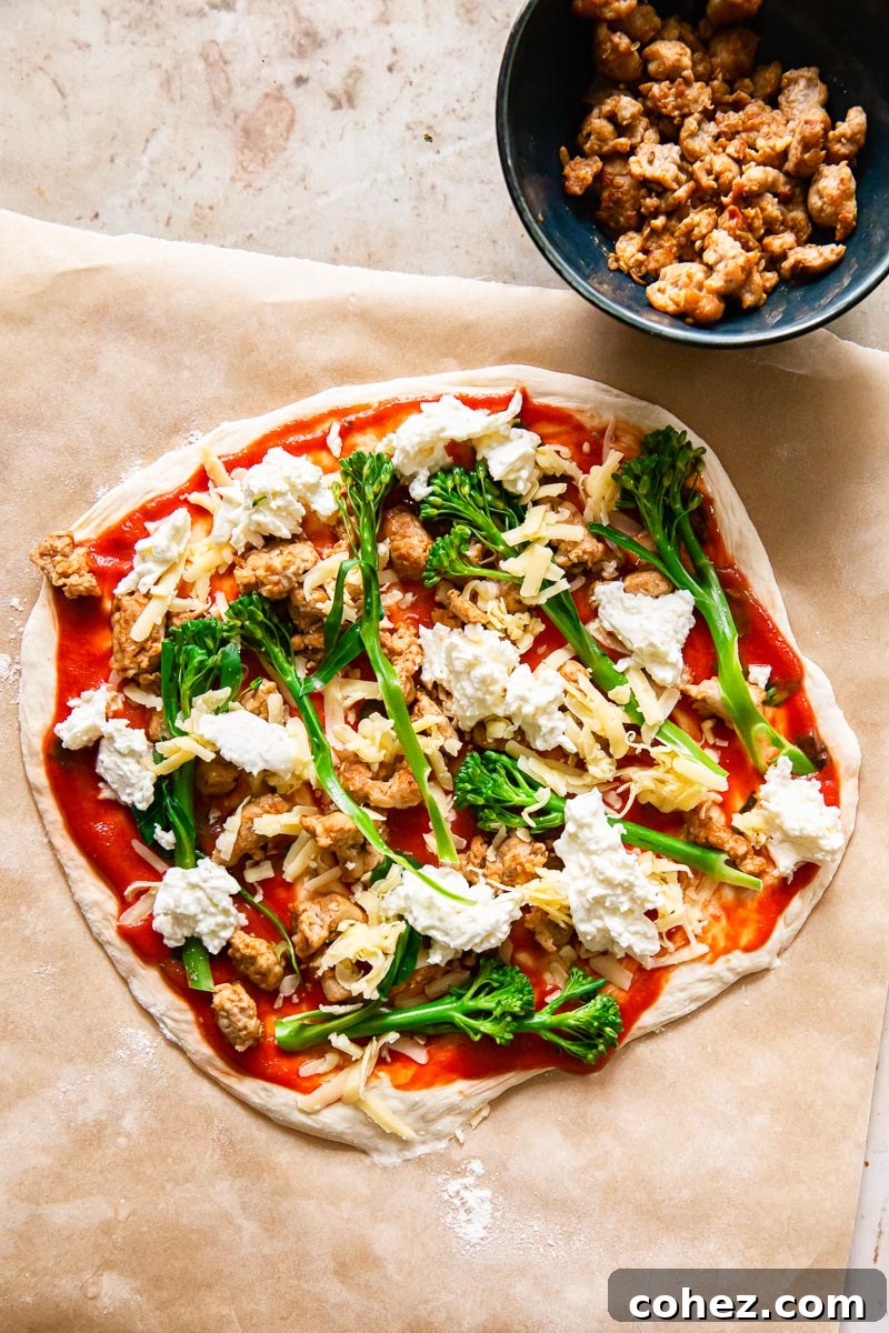 Unbaked sourdough pizza crust, generously topped with savory sausage, fresh broccoli florets, and melted mozzarella cheese, ready for the oven.