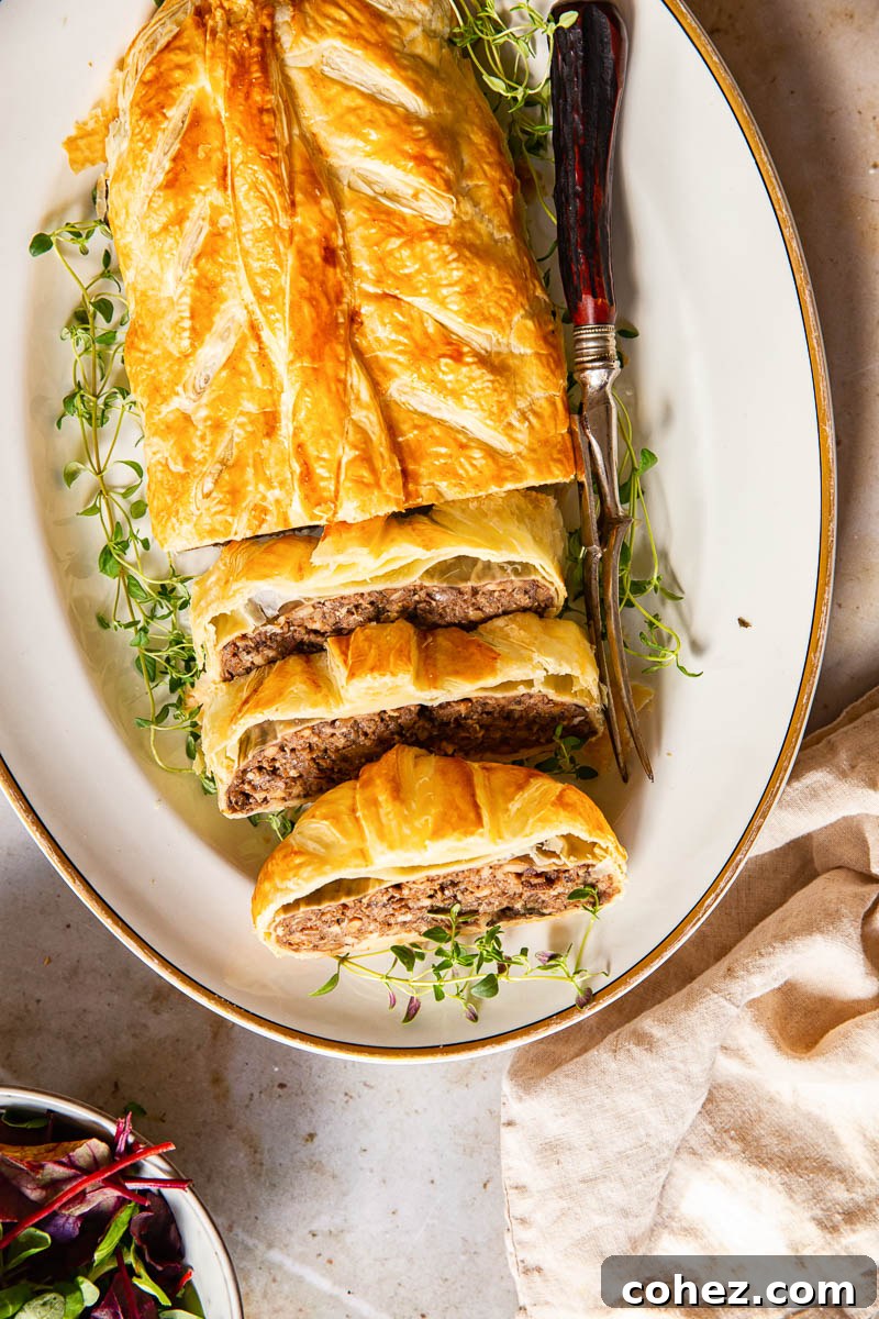 Top-down view of a sliced Mushroom Wellington on a white platter, revealing its rich, textured filling