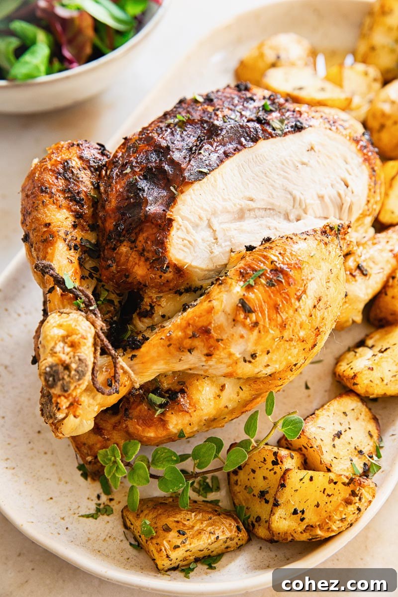 whole chicken on platter with roast potatoes around it