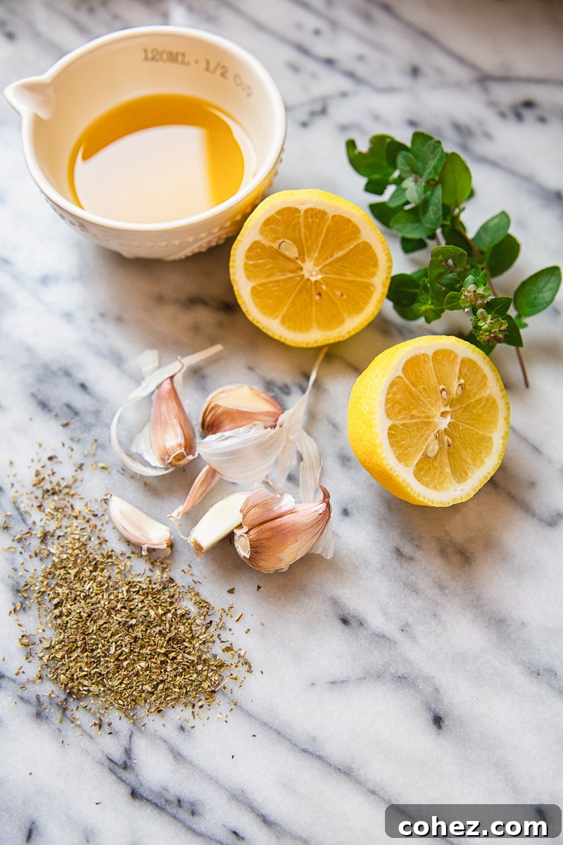 Ingredients for Greek marinade: fresh lemon halves, olive oil, whole garlic cloves, and dried oregano.