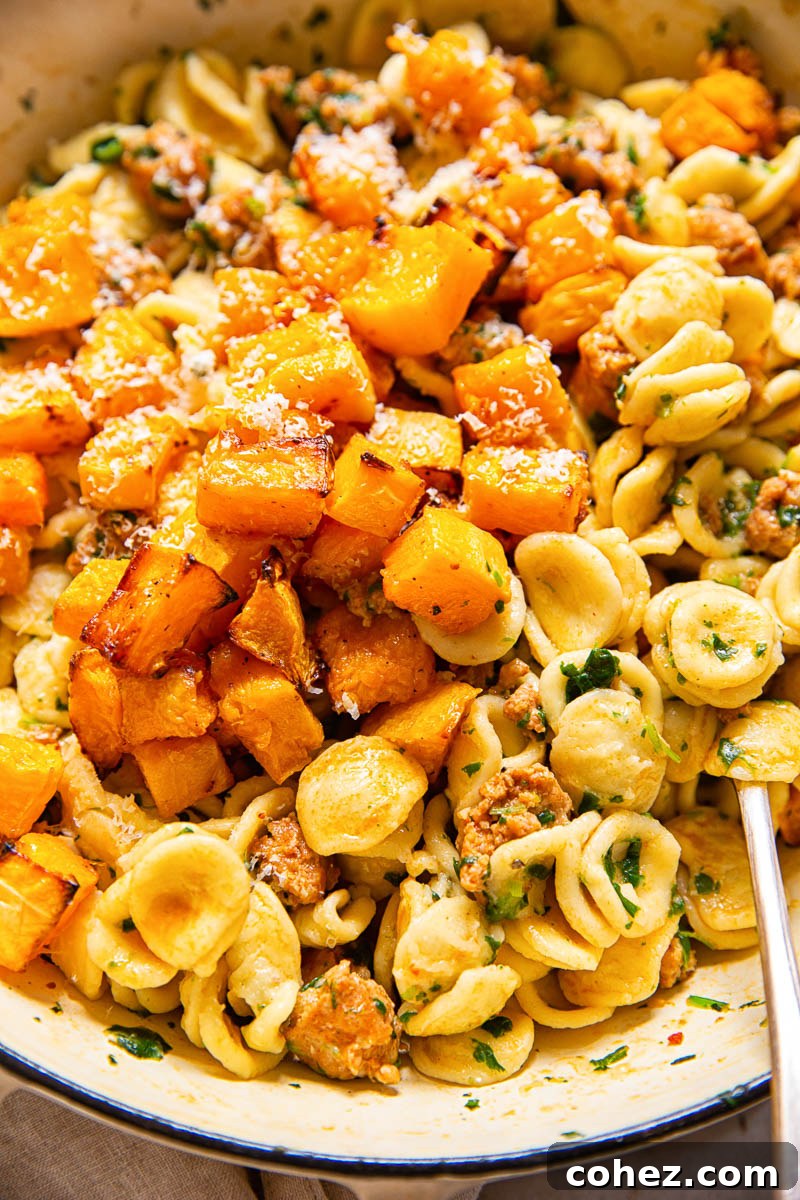 Close-up of roasted butternut squash on top of orecchiette pasta with chorizo and spinach