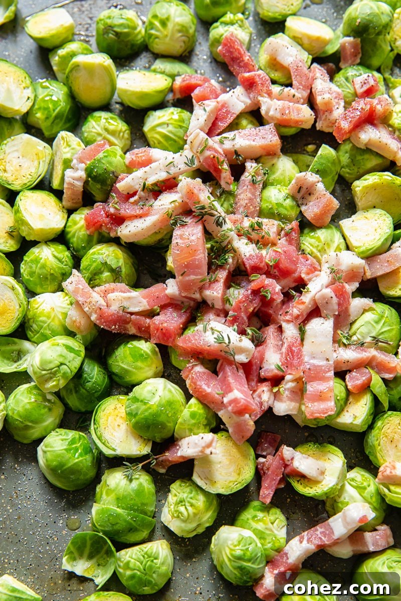 raw brussels sprouts topped with sliced bacon in roasting pan