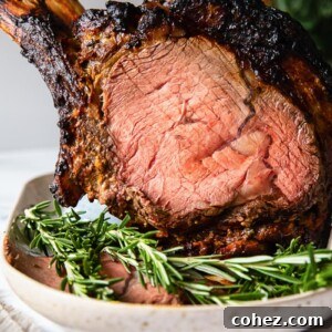 A perfectly cooked prime rib roast, garnished with fresh rosemary, sits on a wooden platter.