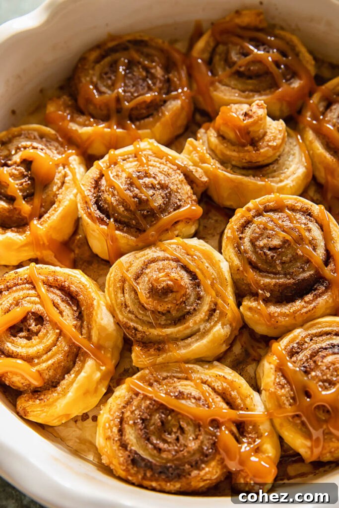 A pie plate filled with freshly baked, golden brown puff pastry cinnamon rolls, ready for topping.