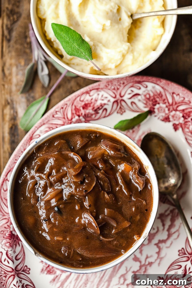 top down view of onion gravy in a bowl and a bowl of mashed potatoes topped with sage leaves