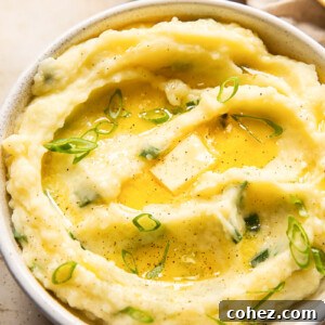 mashed potatoes topped with melted butter and sliced green onions in a bowl