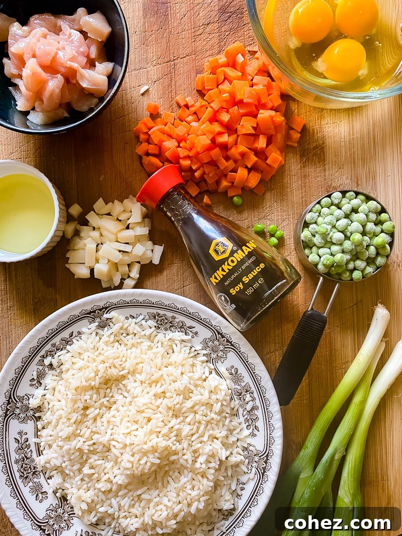 A vibrant selection of ingredients laid out for making chicken fried rice, including rice, chicken, eggs, vegetables, and seasonings.
