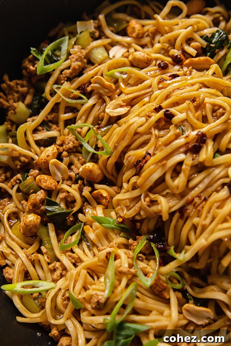 Close-up of a generous portion of Chinese Dan Dan noodles in a wok, ready to be served