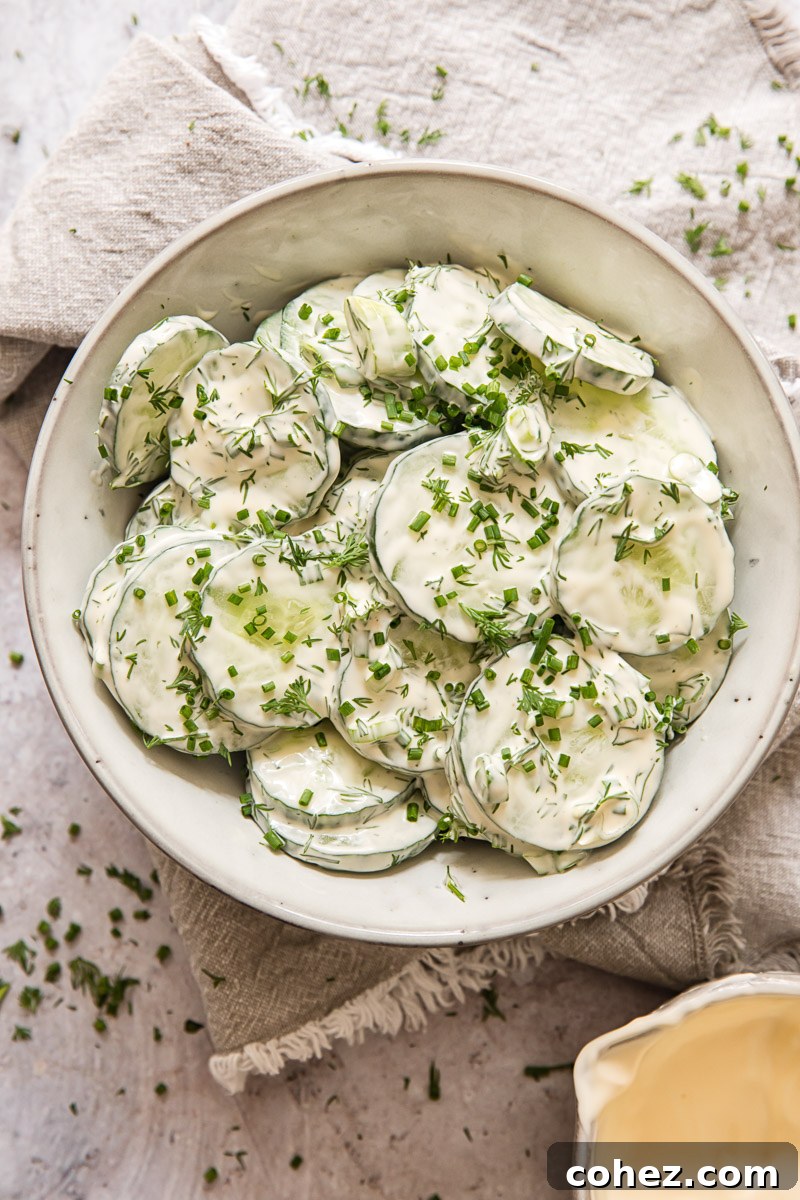 Close-up view of creamy cucumber slices generously coated in dressing in a grey bowl.