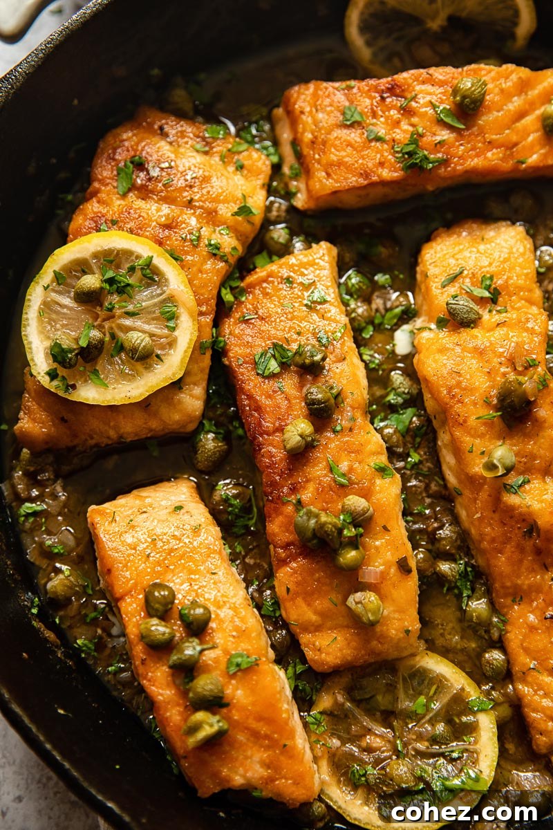 Close-up of golden-brown Salmon Piccata fillets in a cast iron pan, ready to be sauced.