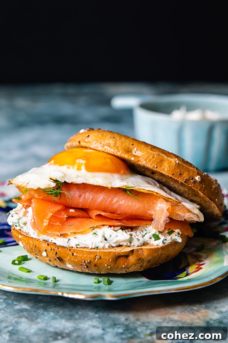 Close-up of a perfectly constructed breakfast sandwich with egg, smoked salmon, and herbed cream cheese nestled in a bagel