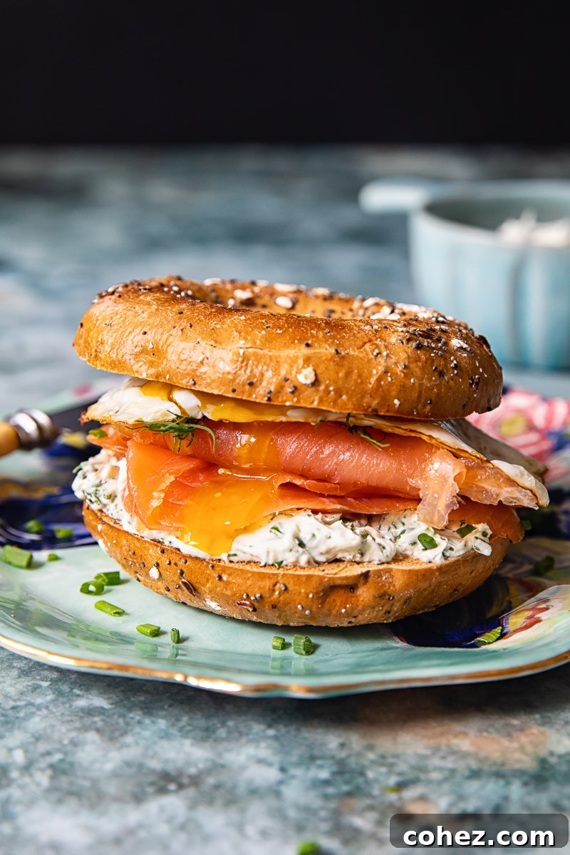 Top view of a beautifully assembled breakfast bagel with smoked salmon, creamy herbed cheese, and a fried egg