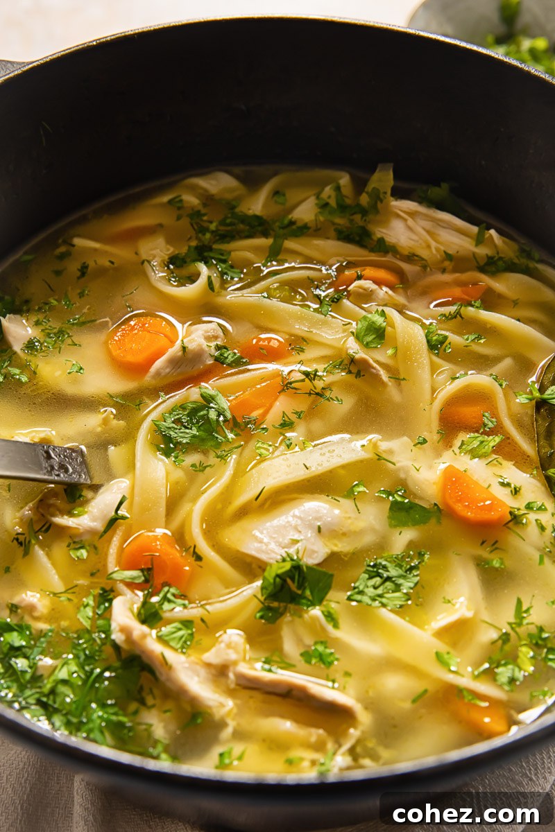 Soul-Warming Chicken Noodle Soup 6 A pot of homemade chicken noodle soup, generously sprinkled with fresh green herbs, showcasing its vibrant freshness and appetizing appeal.