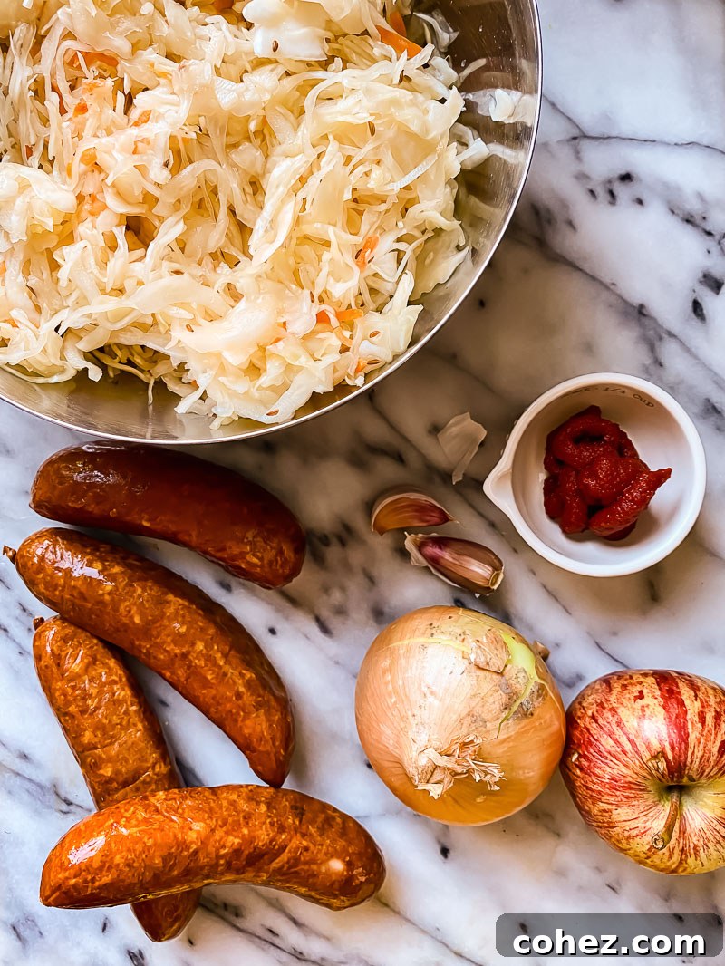 Rustic Kielbasa and Kraut Skillet 3 Ingredients for Kielbasa and Sauerkraut: A bowl of tangy sauerkraut, sliced smoky kielbasa, an onion, a fresh apple, tomato paste, and garlic cloves.