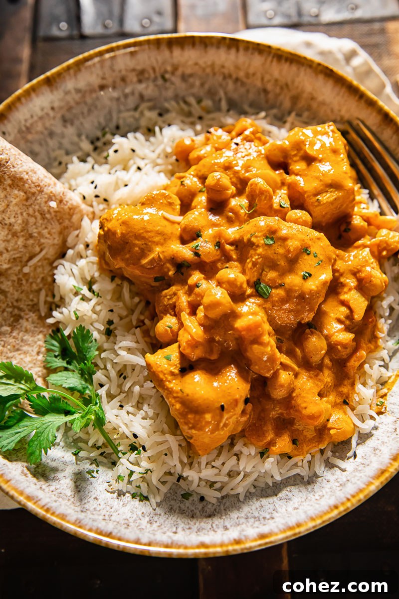 Golden Chicken in a Silken Masala 3 A serving of Chicken Tikka Masala, rich and creamy, served atop fluffy basmati rice in a white ceramic bowl, garnished with herbs.