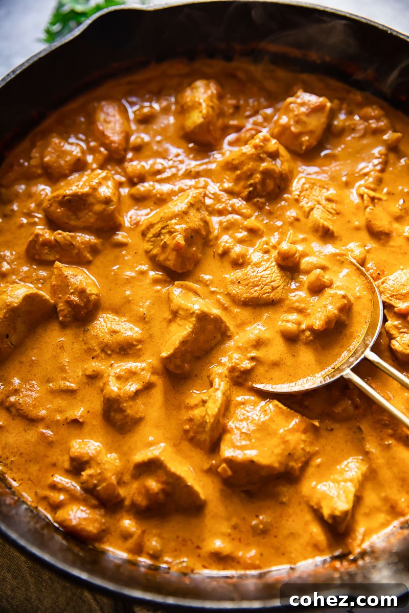 Golden Chicken in a Silken Masala 4 Chicken Tikka Masala generously loaded with chickpeas, simmering in a heavy black pan, ready for its creamy finish.