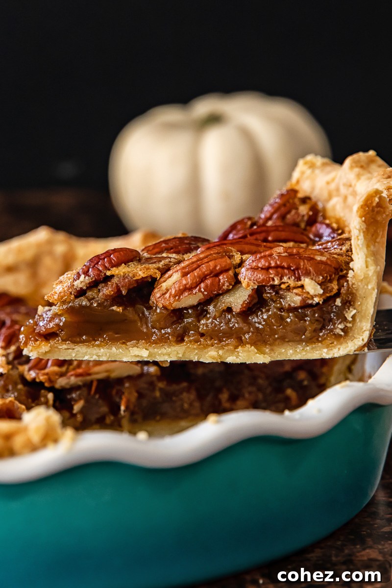 A beautifully sliced Maple Bourbon Pecan Pie, showcasing its golden-brown crust, rich, glossy filling, and perfectly arranged pecans on top, ready for serving.