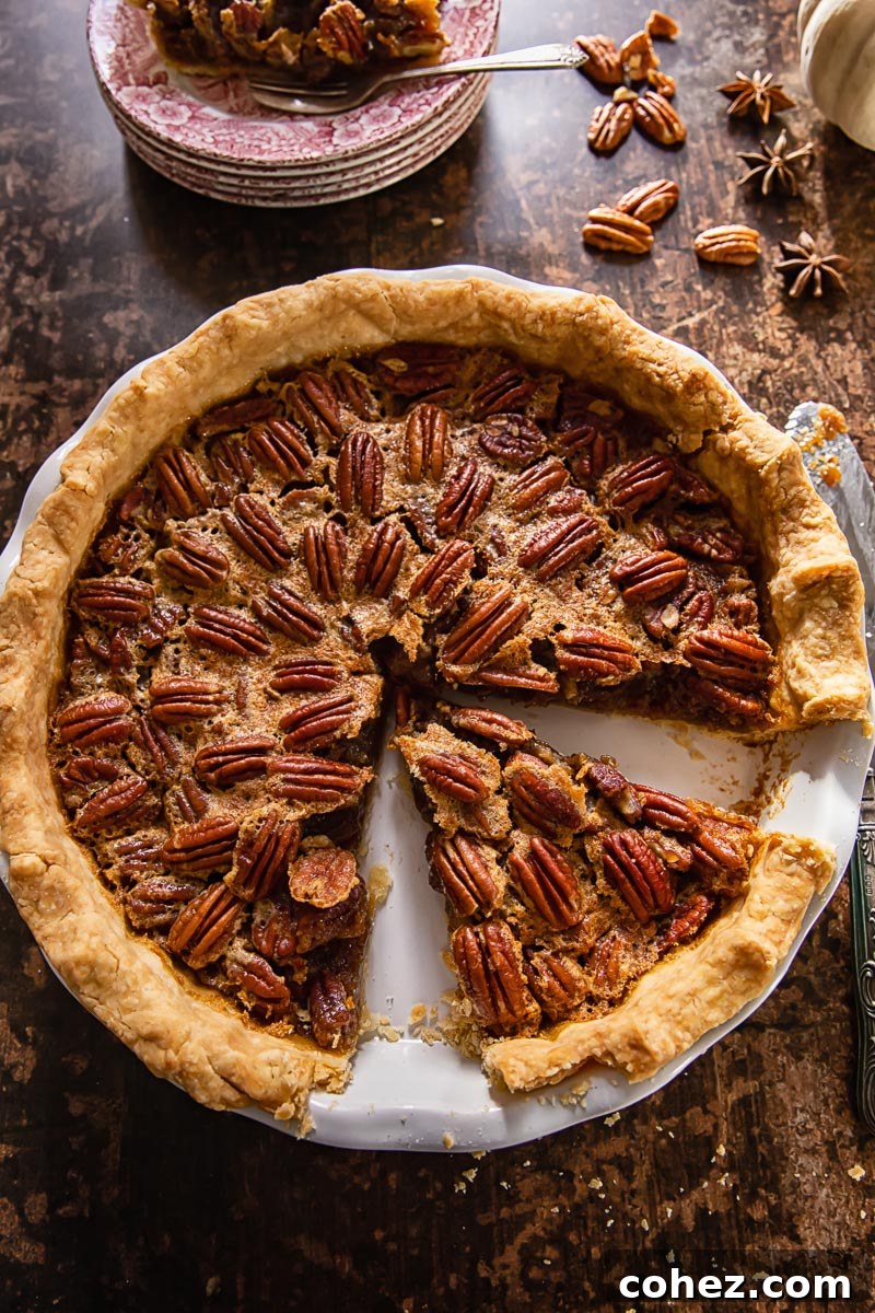 An inviting top-down view of a whole Maple Bourbon Pecan Pie in a pie plate, with a single slice carefully removed to reveal the luscious, nutty filling and perfectly golden crust.