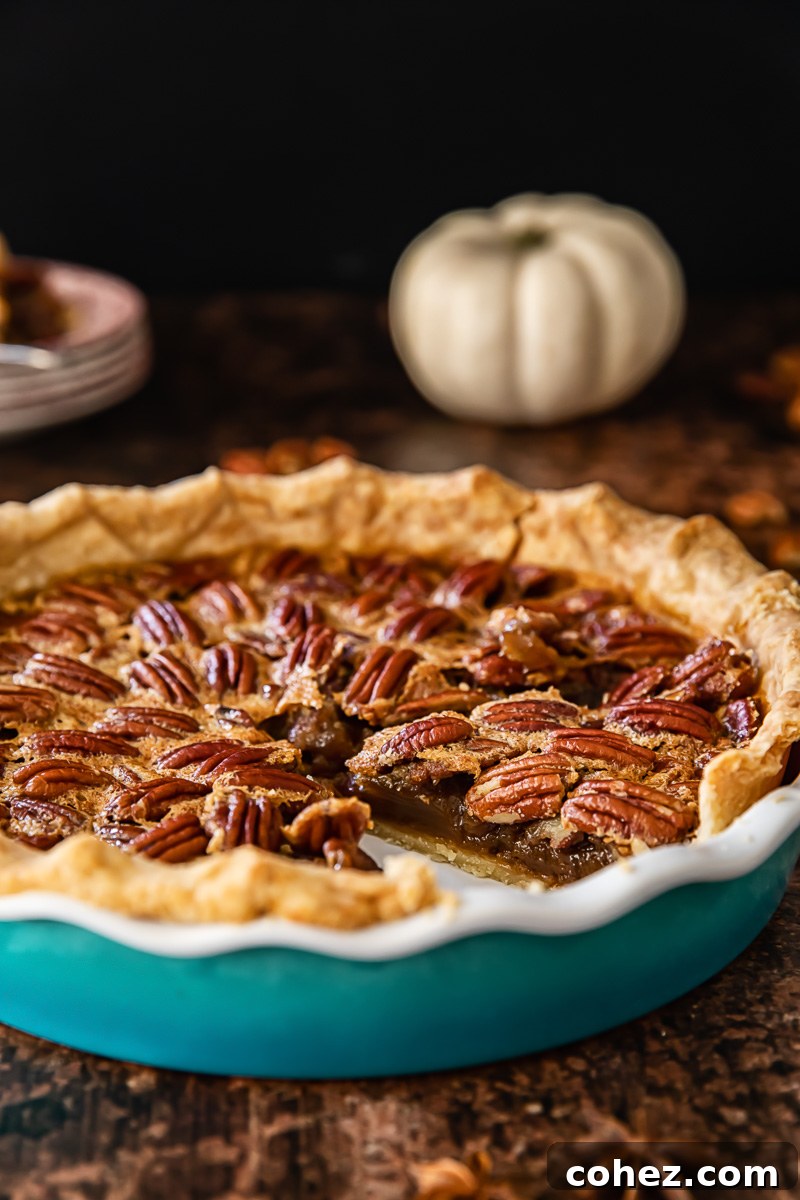 A side profile of a finished Maple Bourbon Pecan Pie in a ceramic pie dish, showcasing its perfectly set filling and golden-brown, beautifully crimped crust.