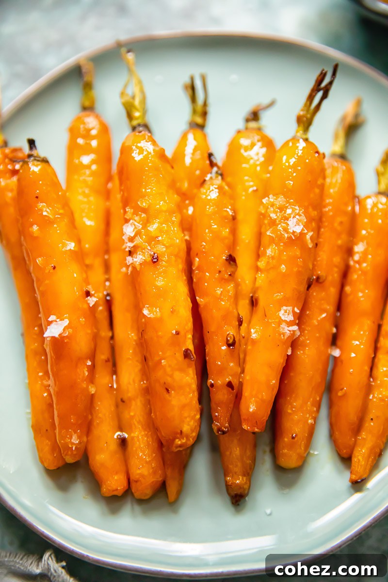 Caramelized Maple Roasted Carrots 2 Glazed carrots elegantly arranged on a blue plate, showcasing their inviting sheen