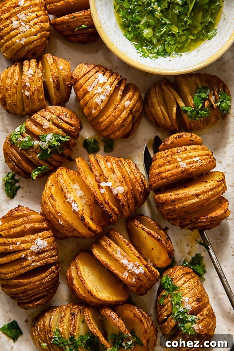 Top down view of crispy hasselback potatoes with a vibrant herb gremolata dip on a wooden board