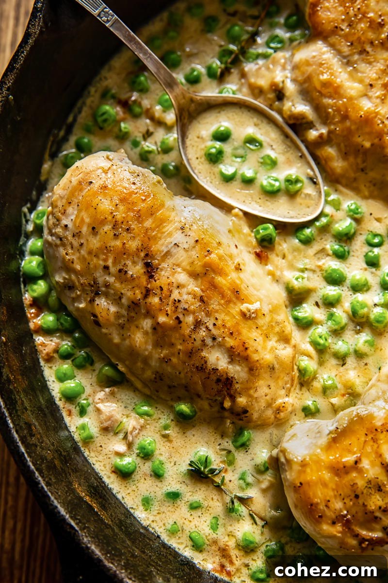close up of chicken breast in a creamy sauce with green peas