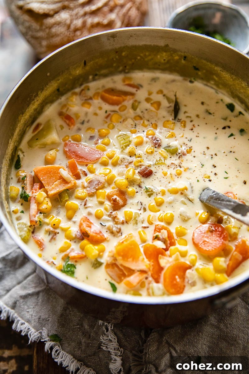 A vibrant, creamy corn chowder brimming with sweet and regular potatoes, and savory bacon, served in a rustic soup pot, ready to be enjoyed.