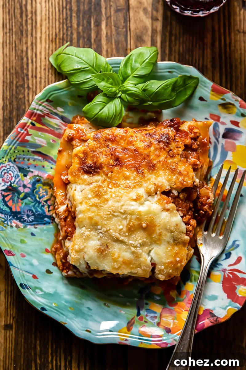 a perfectly cut piece of classic lasagne resting on a blue plate, showing distinct layers