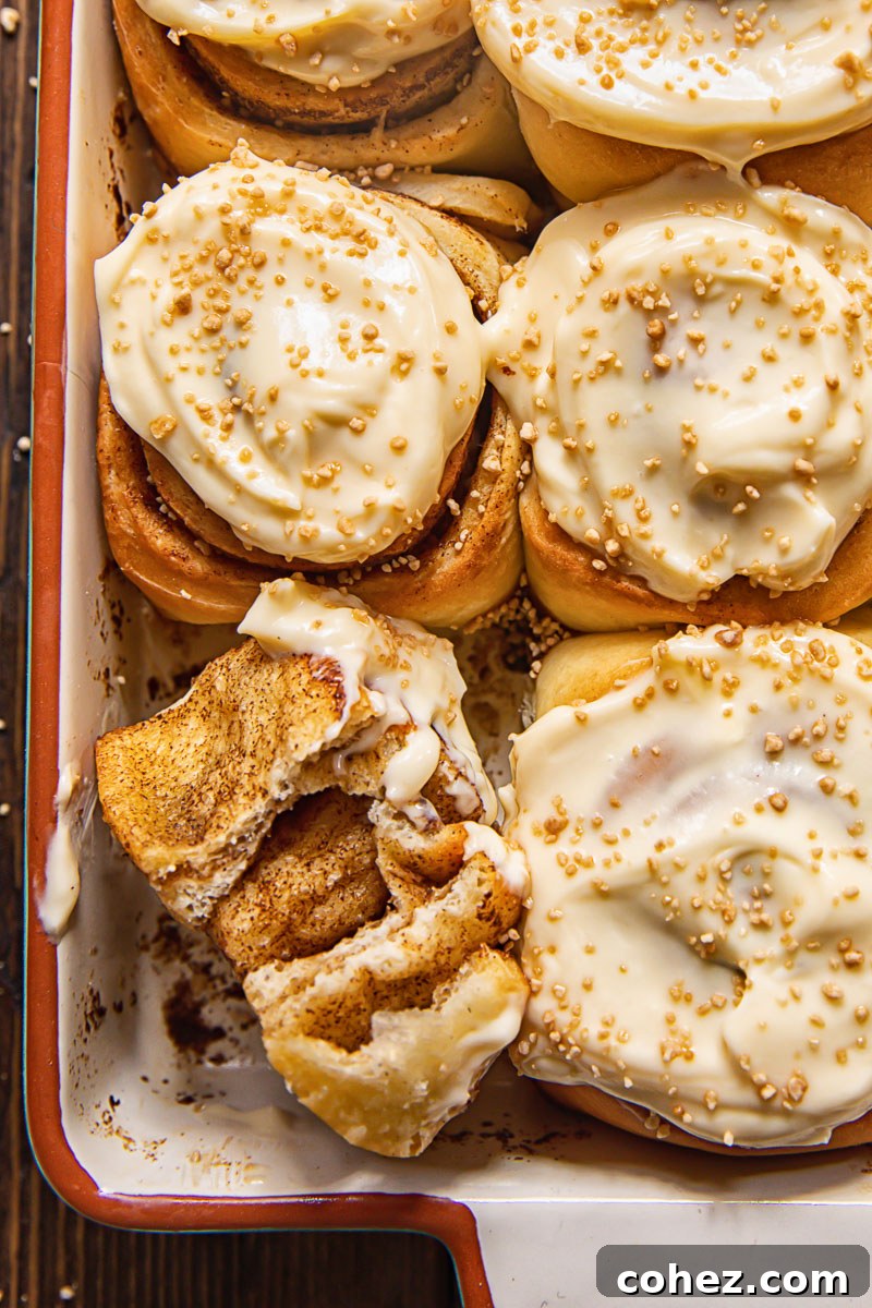 Maple Kissed Cream Cheese Cinnamon Buns 3 Close up of sweet cinnamon rolls with generous dollops of maple cream cheese icing in a baking pan