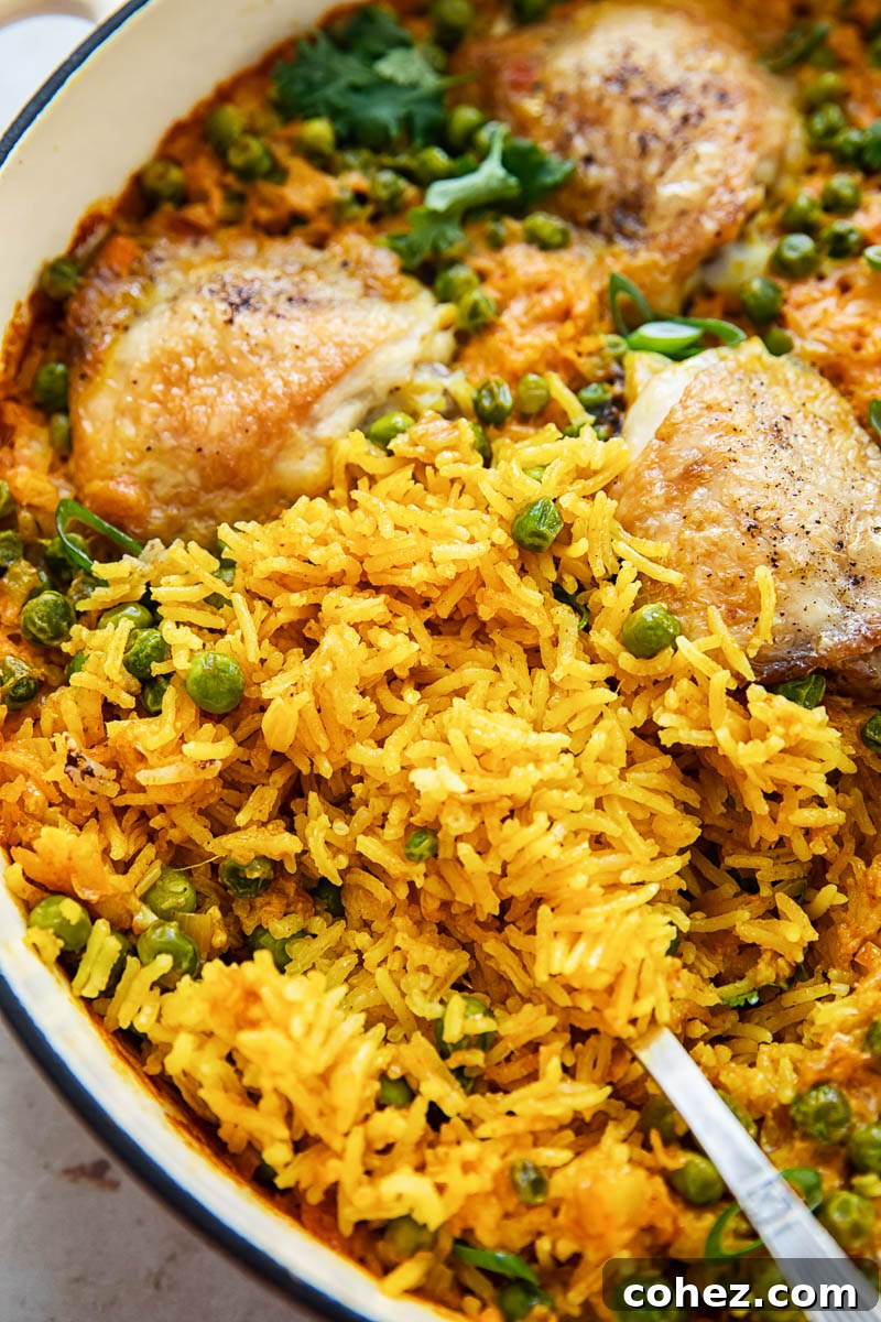 Close-up of fluffy yellow Basmati rice with succulent chicken pieces in a pan, showcasing the texture and rich color.