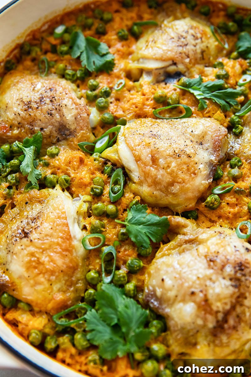 Golden-brown chicken thighs nestled on a bed of turmeric rice in a cast iron pan, ready to be served.