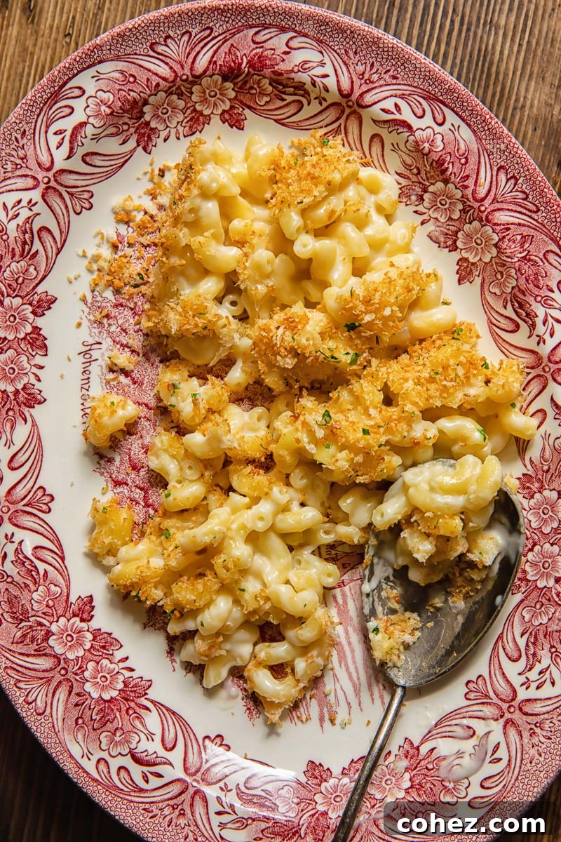 A generous serving of baked macaroni and cheese, glistening with creamy sauce and topped with golden breadcrumbs, presented on an elegant platter.