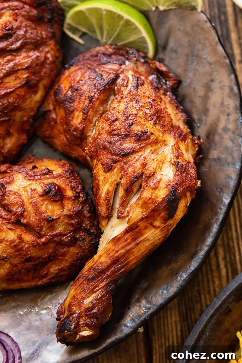 Close-up of a perfectly cooked tandoori chicken leg, showing crispy skin and a rich, spiced crust
